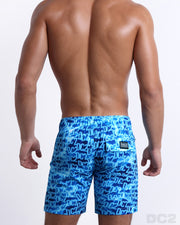 Back view of a male model wearing men’s in WET long boardshorts featuring a monogram print of the DC2 logo print designed by DC2 a brand based in Miami.