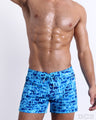 Male model wearing the WET Flex Shorts, premium swimwear with a stylish DC2 logo monogram motif in blue for men. These high-quality swimwear bottoms by DC2, a men’s beachwear brand from Miami.