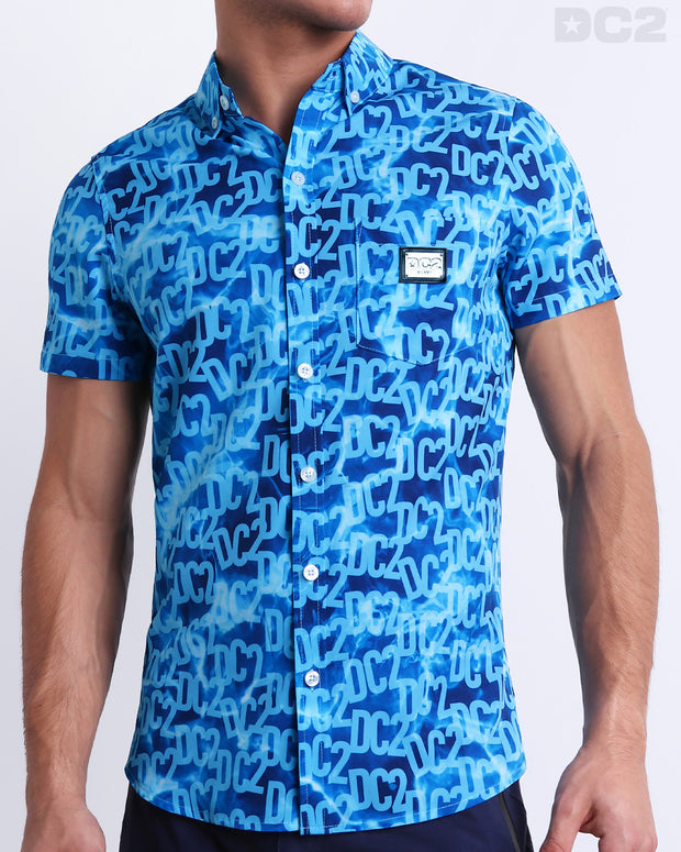 Male model wearing WET men’s sleeveless stretch shirt with stylish DC2 logo monogram motif in blue for men. This high-quality top by DC2, a men’s beachwear brand from Miami. 