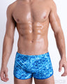 Front view of model wearing the WET men’s Swim Shorts, with a stylish DC2 logo monogram motif print in blue for men. These premium quality swimwear bottoms are DC2 by BANG! Clothes, a men’s beachwear brand from Miami. for men.