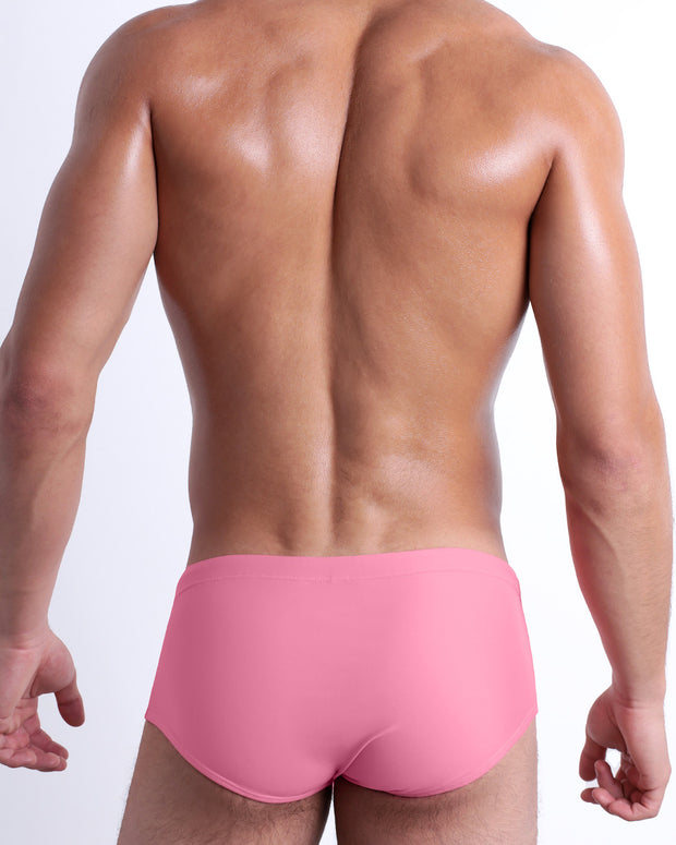 Back view of male model wearing the WHISPERING ROSE beach Brazilian Sunga swimwear for men by BANG! Miami in a solid light pink color.