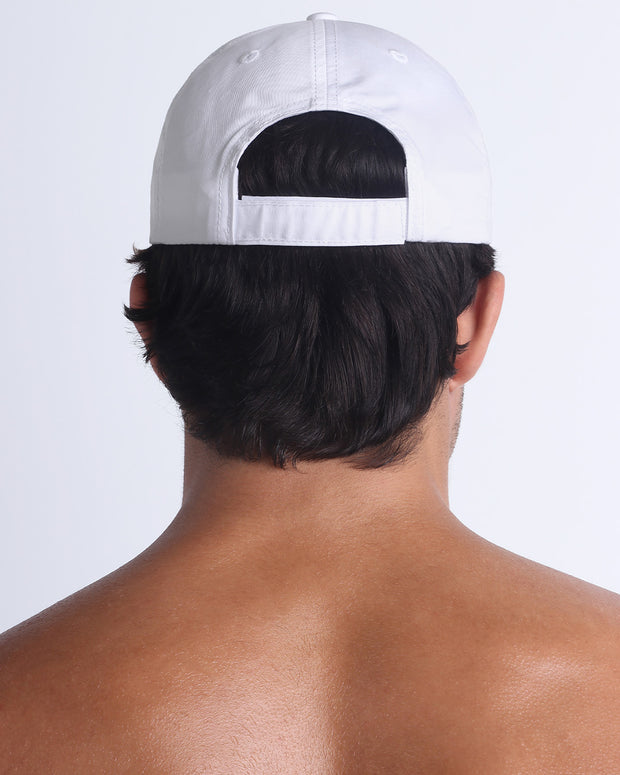 The WHITE Chillax Cap, modeled here, is in solid white. Its adjustable velcro strap at the back ensures a perfect fit for any head size.