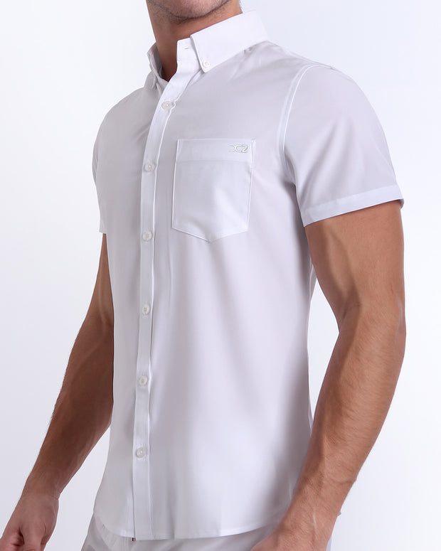 Side view of a masculine model wearing a men’s WHITE PARTY Summer button-down shirt in a solid white color with the official logo of DC2 Miami brand embroidered.