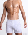 Frontal view of a sexy male model wearing the men’s WHITE PARTY beach tailored shorts in a solid white color. These premium quality swimwear bottoms are DC2 by BANG! Clothes, a men’s beachwear brand from Miami.