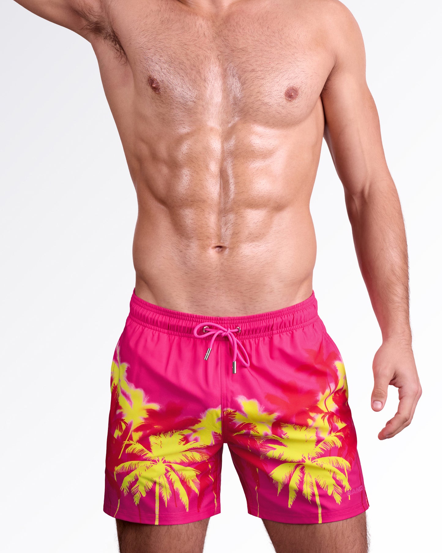 BANG! Miami Wuthering Heights (Fucsia) Resort Shorts — model wearing men’s swim shorts in fucsia pink with yellow palm tree print, featuring elastic waistband with drawstring and relaxed resort fit.