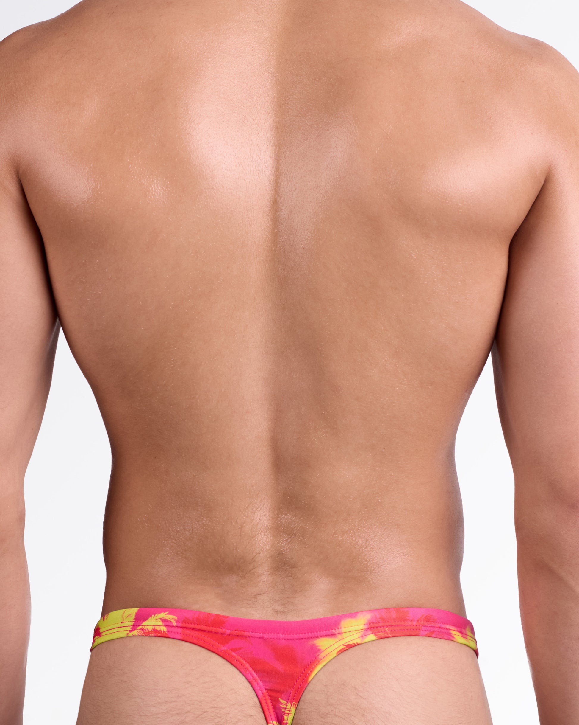 BANG Wuthering Heights (Fucsia) Swim Thong — back view highlighting minimal thong cut, slim waistband, and bold tropical palm design in high-contrast summer tones.