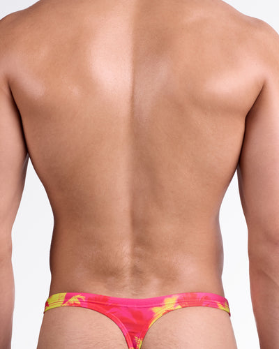 BANG Wuthering Heights (Fucsia) Swim Thong — back view highlighting minimal thong cut, slim waistband, and bold tropical palm design in high-contrast summer tones.