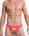 BANG Wuthering Heights (Fucsia) Swim Mini Brief — model wearing pink swim mini brief with neon yellow palm tree print and low-rise tailored fit.