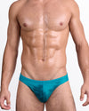 BANG Wuthering Heights (Shades) Swim Mini Brief — model wearing teal gradient mini brief with subtle palm silhouette print and low-rise fit.