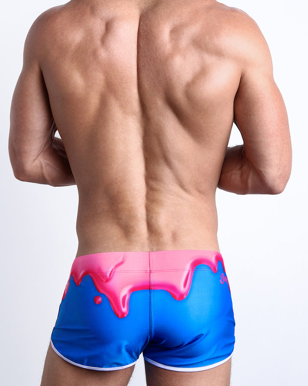 Back view of a male model wearing YOU MELT ME men’s swim shorts featuring magenta pink melting ice cream print by the Bang! Clothes brand of men&