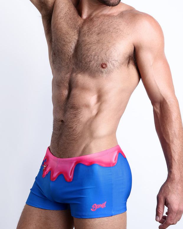 Side view of a masculine model wearing the YOU MELT ME compression swimwear shorts featuring magenta pink melting ice cream print by BANG! Clothes.