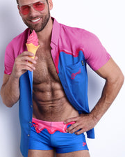 Frontal view of a male model wearing the YOU MELT ME Swim Trunks and the matching Stretch Shirt featuring magenta pink melting ice cream print by BANG! Clothes based in Miami, FL.