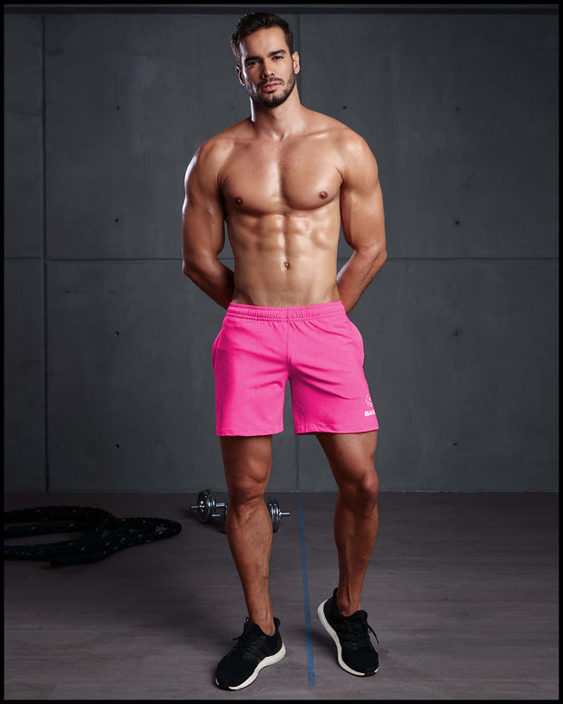 Male model wearing the PINKTENSITY Jogger Shorts. These men’s sport shorts are form-fitting shape of a tight jogger.