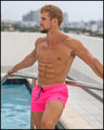 Sexy male model by the pool wearing the PINK BOMB Show Shorts. These shorts have two slip pockets at the front for wallets, keys, or ID's.