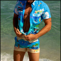 Male model at the beach wearing the 8-BIT WILD BEACH PARTY - Stretch Shirt inspired Hawaiian shirt for men with pixelated sprite graphics of Atari video game, Nintendo, Sega, Commodore 64 by BANG! Clothes the official brand of men’s beachwear.