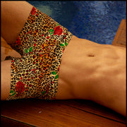 View of a sexy model by the pool wearing the CATS N'ROSES men’s swim bottoms featuring leopard print in brown tones with red roses by the Bang! menswear brand from Miami.