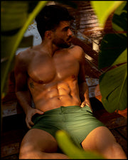 Male model wearing the ALPHA GREEN men’s swim tailored shorts in army green color by the Bang! brand of men's beachwear from Miami.