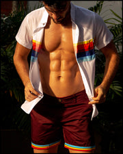 Front view of a male model wearing men's chino shorts in bold dark red color with cuff in stripes light blue, yellow and red color with a mix and match stretch shirt by BANG! Miami Clothes brand.