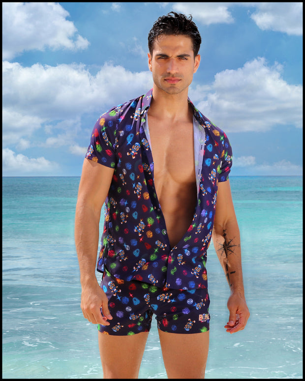 View of model wearing the HEY MISTER TJ (CLUB MIX) Men’s beach trunks and matching stretch shirt by BANG! with clubbing and disc-jockey details in dark colors.