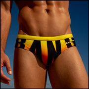 Front view of the BIG BANG GOLDEN HOUR men’s summer swimsuit bottoms with giant BANG! letters in black over a bright yellow, orange and red gradient background.