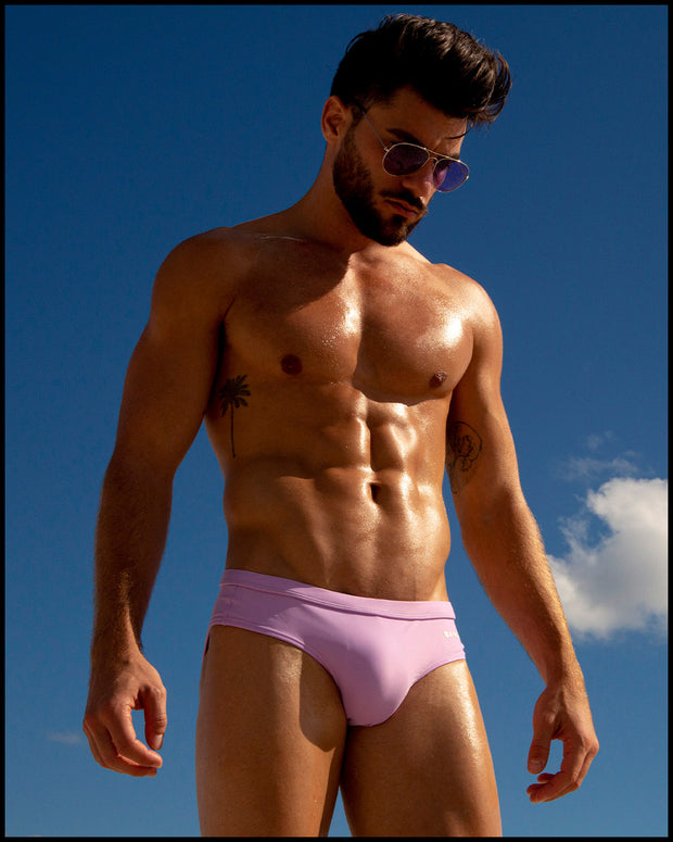 Sexy male model wearing men’s swimsuit in bright purple color made with Italian-made Vita By Carvico Econyl Nylon by the Bang! Menswear brand from Miami.