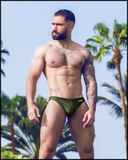 Frontal view of a sexy male model wearing men’s swimsuit in dark green color by the Bang! Menswear brand from Miami.
