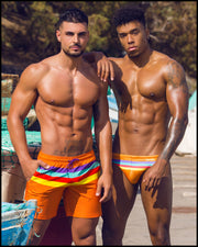 Frontal view of models by boats wearing Stripe A Pose men's swimwear by the Bang! Clothing brand of men's beachwear from Miami.