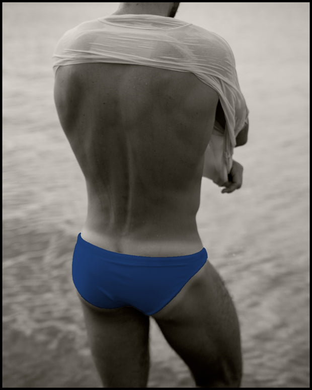 View of a male model posing wearing men’s swim mini-brief in VOULEZ-BLUE a cobalt blue color by the Bang! Clothes