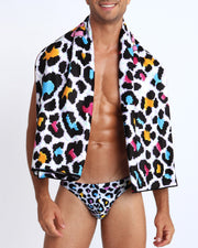 Front view of a sexy male model wearing an 8 bit pop leopard swim brief in blue white pink and yellow by Bang Miami