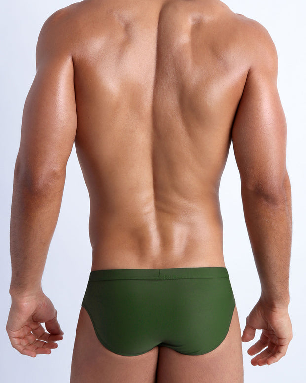 Back view of a male model wearing men’s swim briefs Made with Italian Recycled Nylon Vita by Carvico Econyl in smooth hunter green color by the Bang! Clothes brand of men&