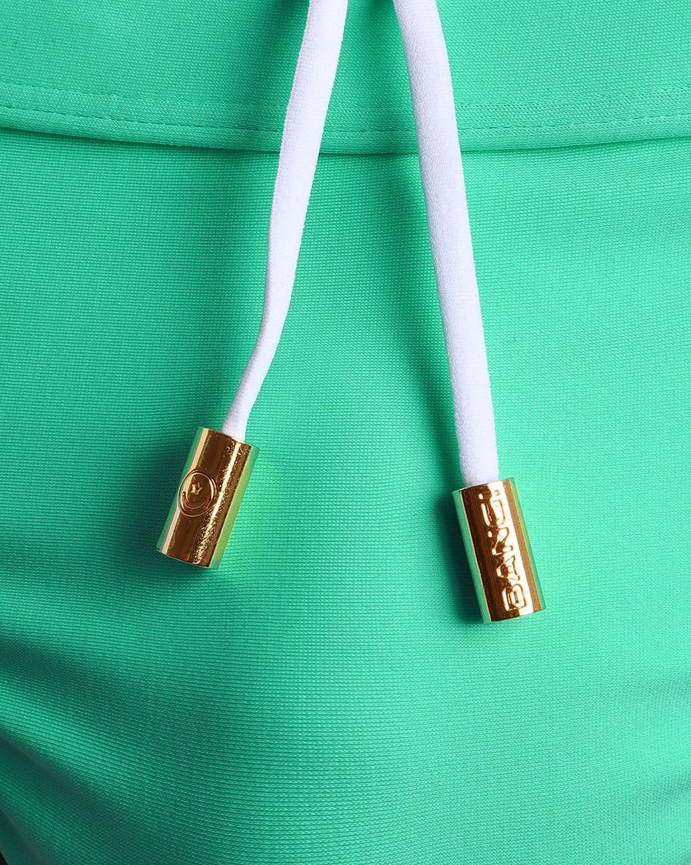 Close-up view of men’s summer swimwear by BANG! clothing brand, showing white cord with custom branded golden cord ends, and matching custom eyelet trims in gold.