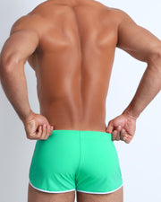 Back view of a male model wearing men’s swim brief in light green by the Bang! Clothes brand of men's beachwear from Miami.