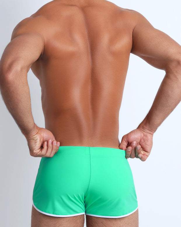 Back view of a male model wearing men’s swim brief in light green by the Bang! Clothes brand of men&