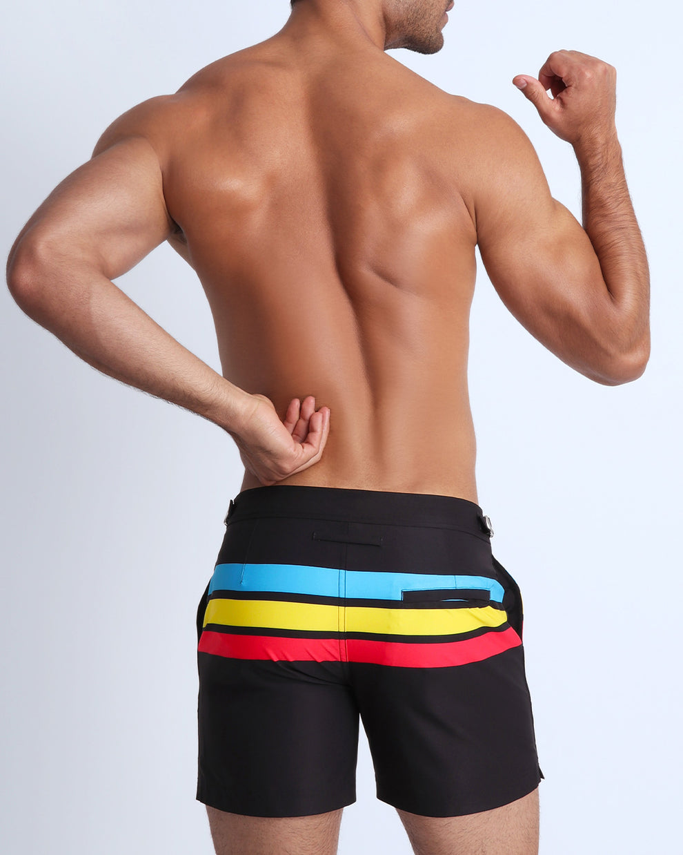 Back side view of male model wearing men's swimwear in black color with color stripes in turquoise blue, yellow, and red.