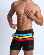 Front view of a sexy male model wearing BANG Miami premium tailored shorts in black with colored stripes red yellow blue lgbtq
