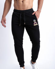 Frontal view of male model wearing the BANG! Clothes BLACK Tracksuit Pants with frontal drawstring closure. This athletic jogger has an embroidered Bang! Logo with the signature Mister TJ tiger. 