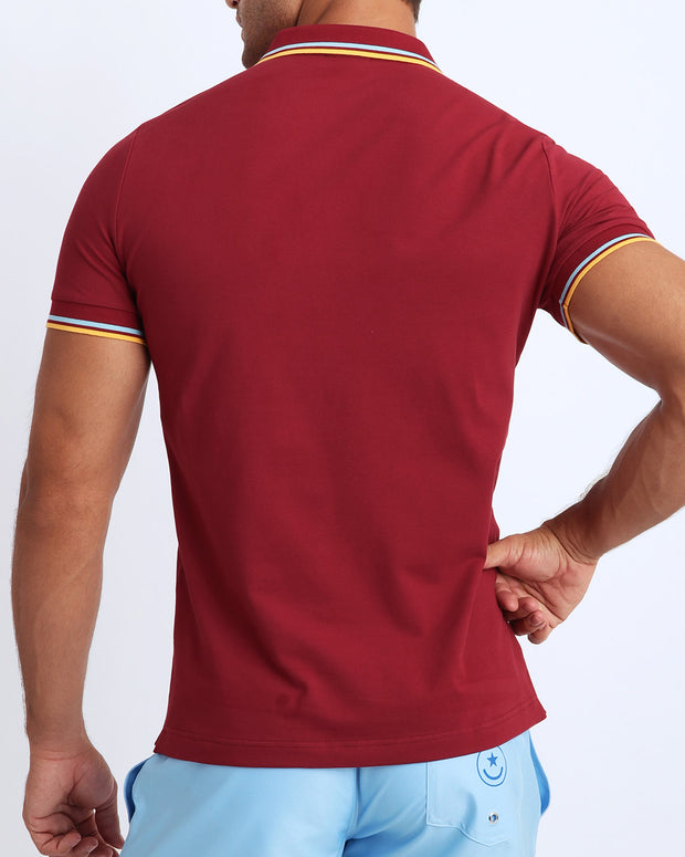 Back view of a sexy model wearing a short-sleeve classic polo shirt for men in a wine color from BANG! Clothing the official brand for menswear.