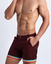 Left side view of stretchy men's shorts in  wine color with reversible cuffs with stripes light blue, yellow and red color from BANG! Clothing.