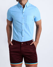 Male model wearing men's deep dark red color chino shorts with stripes light blue, yellow and red color and short sleeve shirt for men in light blue color