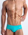 Frontal view of a sexy male model wearing men’s swimsuit in cerulean blue color by the Bang! Menswear brand from Miami.