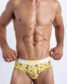 Front view of a sexy male model wearing a BANG! Cotton briefs for men in a soft yellow features a fun pineapple print with the hashtag forever wild offering a perfect fit.