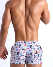 Back view of model wearing the HEY MISTER TJ (POOLSIDE MIX) Men’s beach trunks by BANG! with clubbing and disc-jockey details in dark colors.