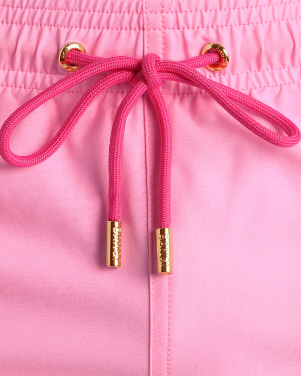 Close-up view of the LA BEACH EN ROSE men’s summer shorts, showing hot pink cord with custom branded golden cord ends, and matching custom eyelet trims in gold.