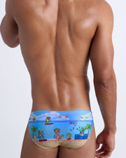 Male model's back view showing the 8-BIT WILD BEACH PARTY beach mini-briefs for men with vintage  sprite graphics of  Atari video game, Nintendo, Sega, Commodore 64