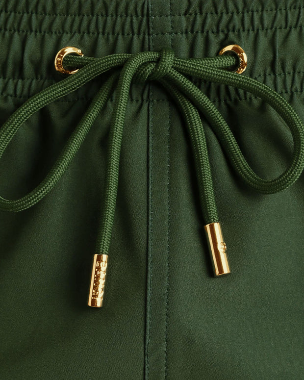 Close-up view of inseam and details of these shorts for men, with green cord and custom branded golden cord-ends, and matching custom eyelet trims in gold.