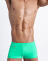 Frontal view of a sexy male model wearing men’s swimsuit made with Italian-made Vita By Carvico Econyl Nylon with mini pocket in bright aqua bold color by the Bang! Menswear brand from Miami.