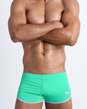 Frontal view of a sexy male model wearing men’s swimsuit made with Italian-made Vita By Carvico Econyl Nyloni n bright aqua bold color by the Bang! Menswear brand from Miami.