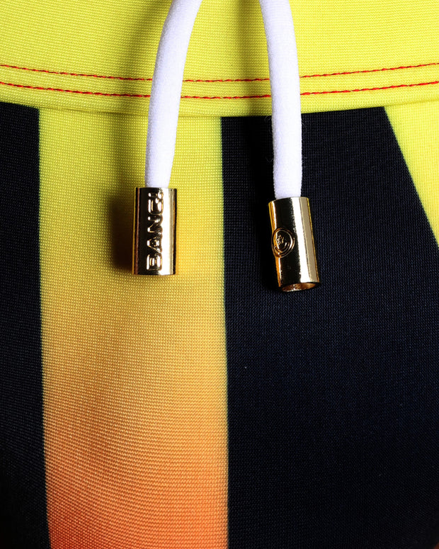 Close-up view of men’s summer shorts by BANG! clothing brand, showing white cord with custom branded golden cord ends, and matching custom eyelet trims in gold.