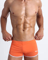 Frontal view of a sexy male model wearing men’s swimsuit in tangerine color by the Bang! Menswear brand from Miami.