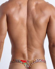 Male model's back view showing the CATS N'ROSES beach swim bikini for men featuring animal print of brown cheetah with red roses by Bang! Miami.